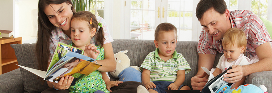 Mom and dad on the couch reading with their three kids